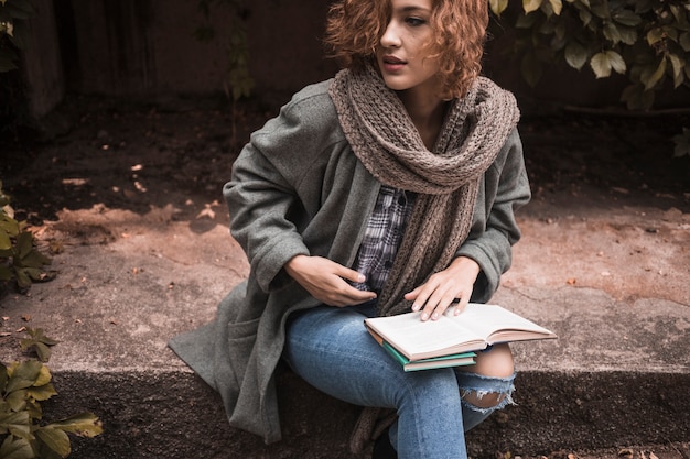 Free photo woman sitting on board and holding opened book