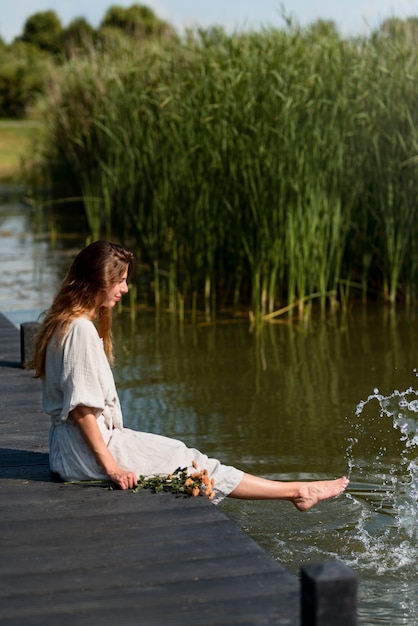 Free Photo woman sitting by the lake full shot