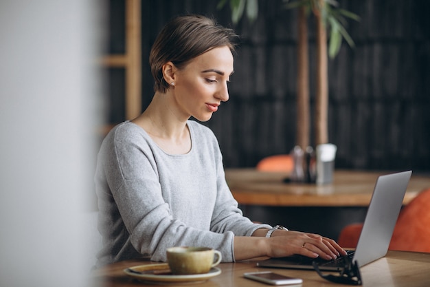 Free photo woman sitting in a cafe drinking coffee and working on a computer