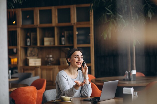 Woman sitting in a cafe drinking coffee and working on a computer