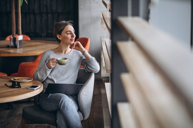 Woman sitting in a cafe drinking coffee and working on a computer