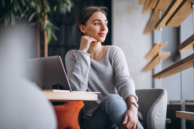 Woman sitting in a cafe drinking coffee and working on a computer