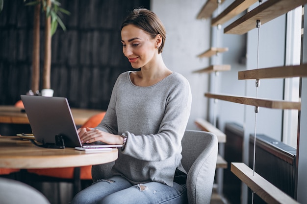 Free photo woman sitting in a cafe drinking coffee and working on a computer