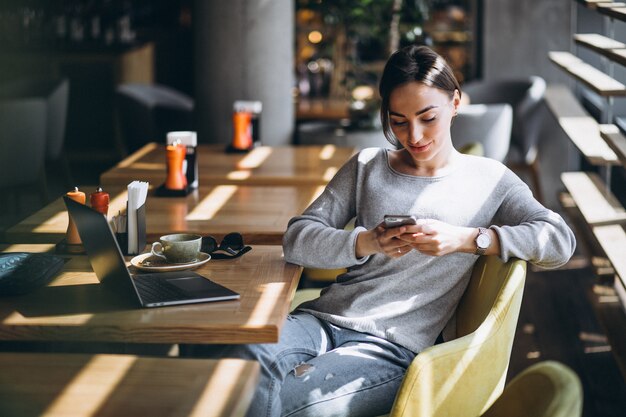 Woman sitting in a cafe drinking coffee and working on a computer