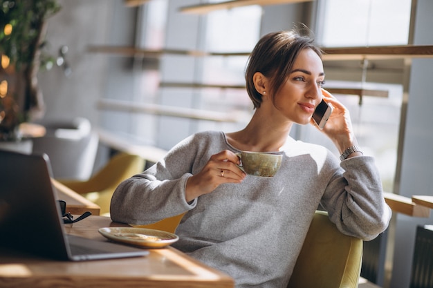 Woman sitting in a cafe drinking coffee and working on a computer