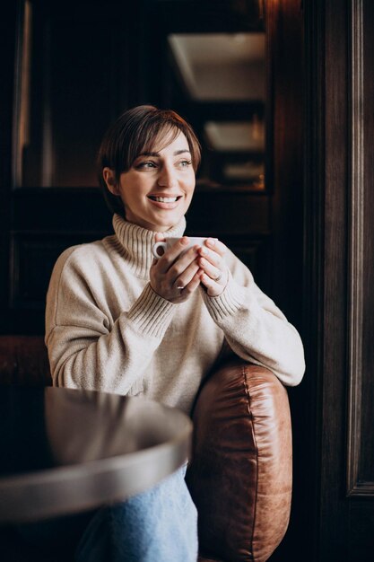 Woman sitting in a cafe and drinking coffee