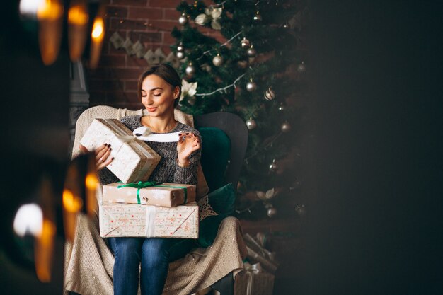 Woman sitting in chair by Christmas tree