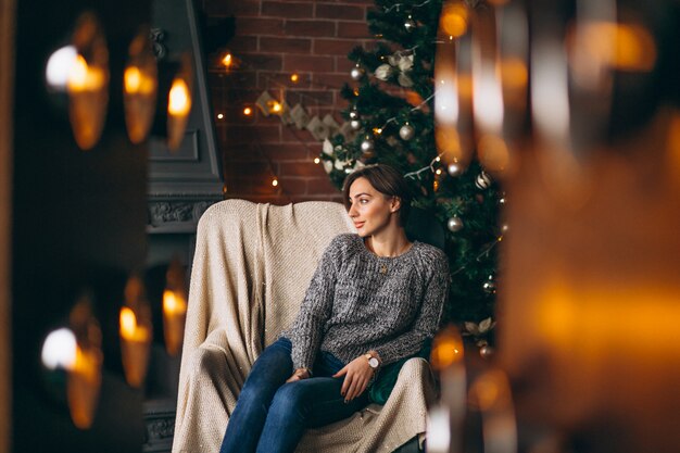 Woman sitting in chair by Christmas tree