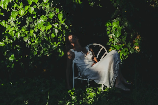 Free photo woman sitting on chair near bushes