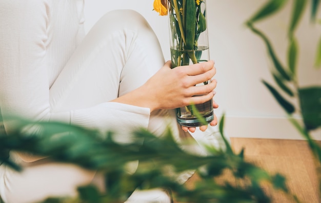 Free Photo woman sitting on floor with flowers in vase 