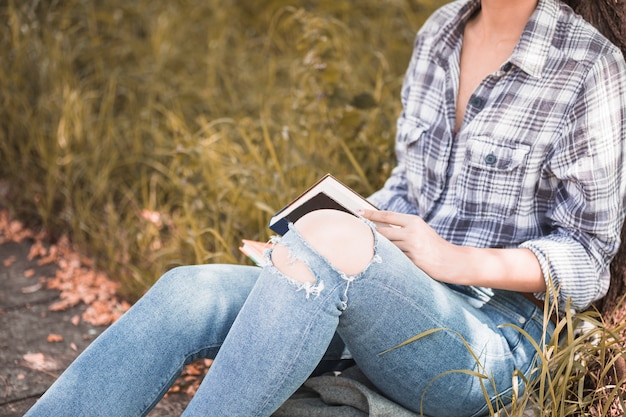 Free photo woman sitting on grass and holding volume