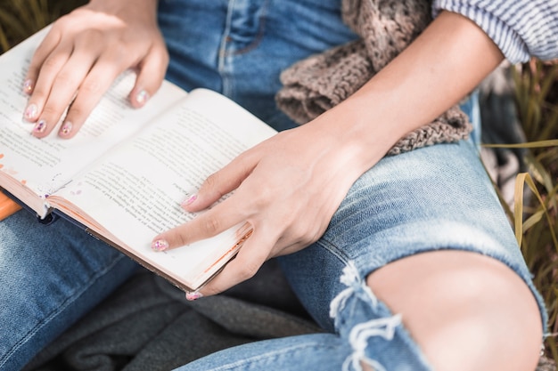 Free photo woman sitting on grass with book and following text by hand