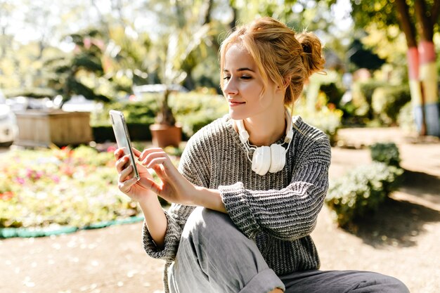 woman sitting in greenhouse takes selfie on her phone