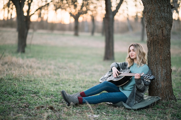 Free Photo woman sitting on ground with guitar