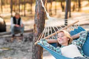 Free photo woman sitting in hammock blurred man in background