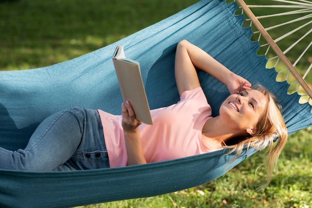 Woman sitting in hammock and holding a book high view