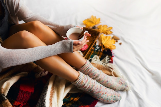 woman sitting in her bed with books and drinking coffee with cinnamon, cookies and glazed donuts.