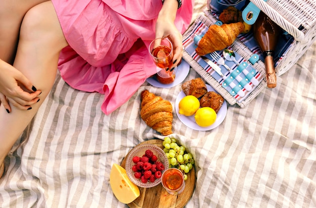 Free photo woman sitting and holding glass of champagne, traditional fruits, croissants and cheese,