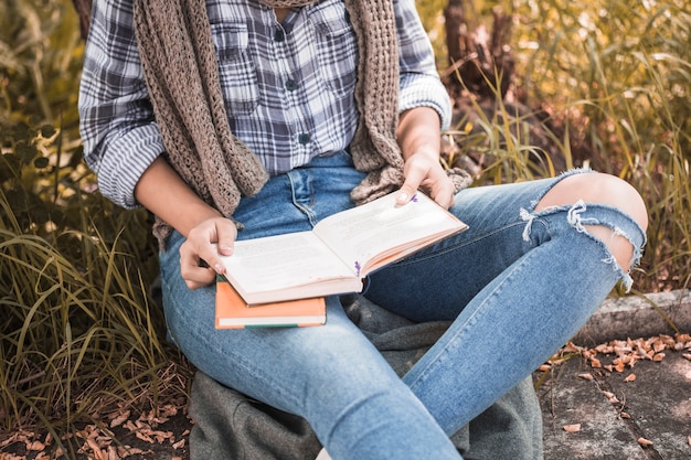 Free photo woman sitting on lawn and holding opened book