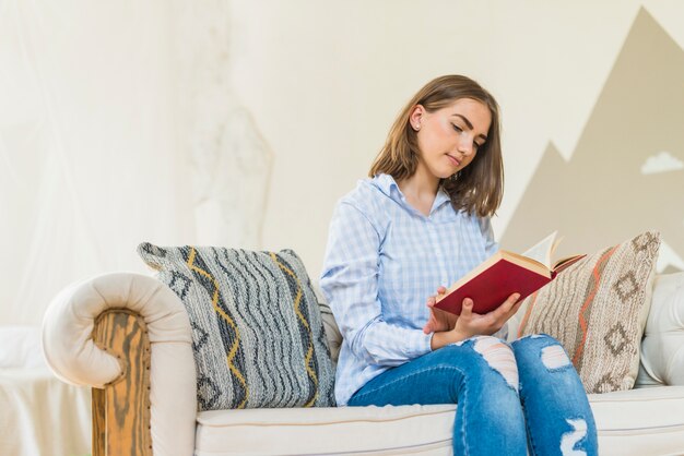 Woman sitting in living room on couch reading book