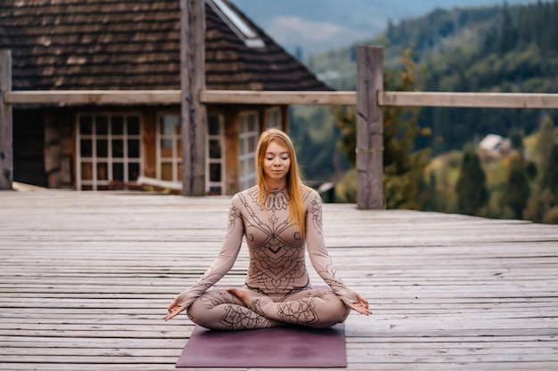 A woman sitting in lotus position at the morning on a fresh air.