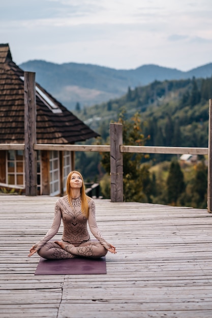 Free photo a woman sitting in lotus position at the morning on a fresh air.