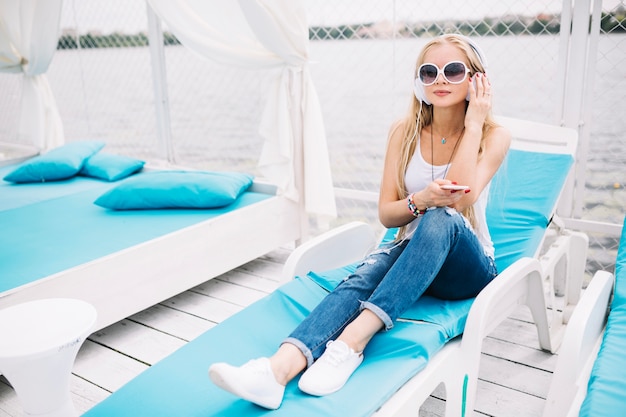 Free photo woman sitting on lounge with headphones