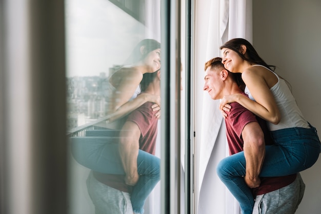 Woman sitting on man back and looking at window