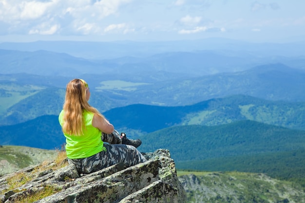 Free photo woman sitting on mountain peak