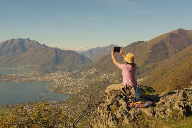 Woman sitting on a mountain and taking pictures of the beautiful lake view in Switzerland