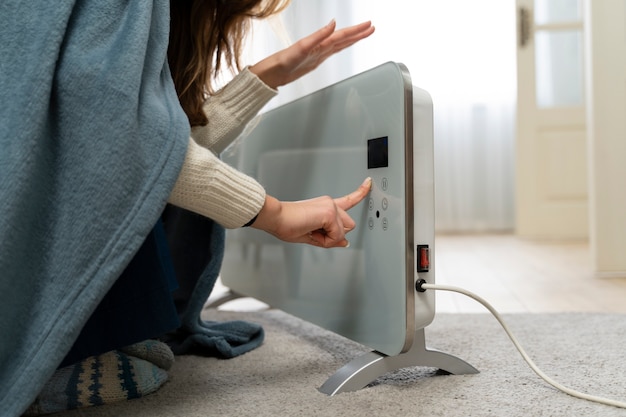 Free photo woman sitting near heater at home