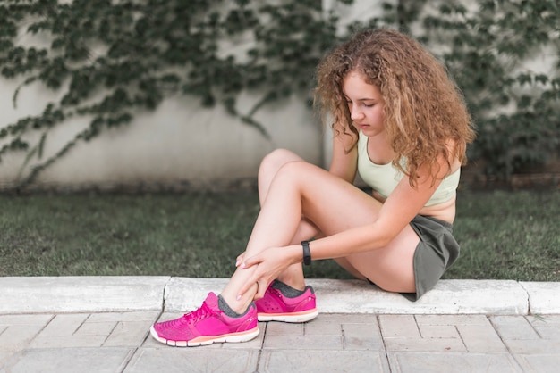 Woman sitting in the park looking at injured ankle