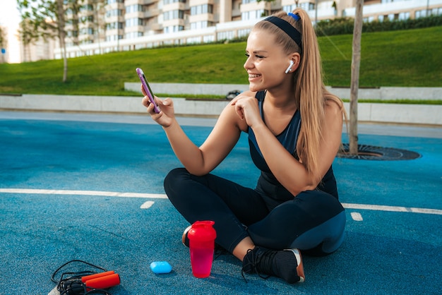 Woman sitting on the playground with a phone in her hands