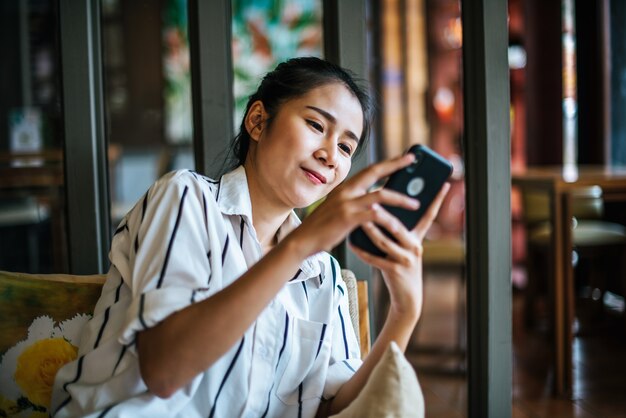 Woman Sitting and playing her smart phone at cafe