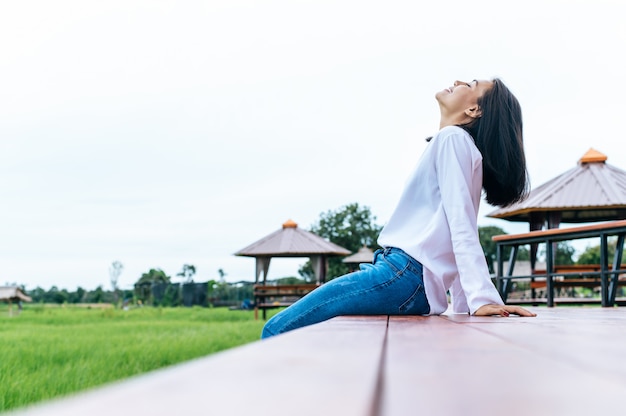 Woman sitting and relax on Wood bridge with their legs hanging down