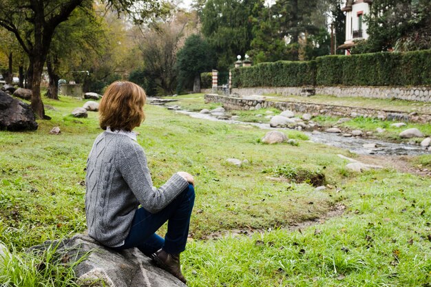 Woman sitting on rock near river