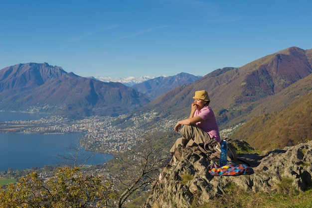 Woman sitting on the rock with a beautiful view of mountains near the seashore