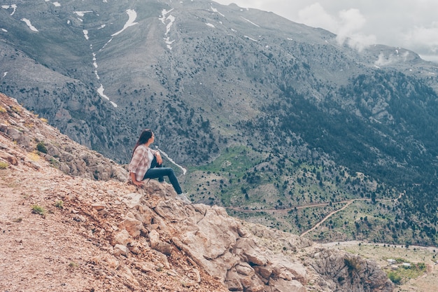 woman sitting on rocks, enjoying the view and thinking in hills during daytime 