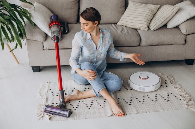 Free photo woman sitting on sofa and choosing vacuum cleaner