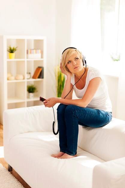 woman sitting on the sofa and wondering about some music