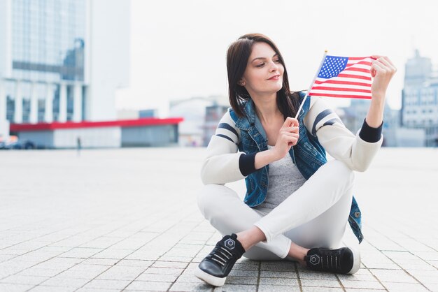 Woman sitting on square and holding American flag in hand