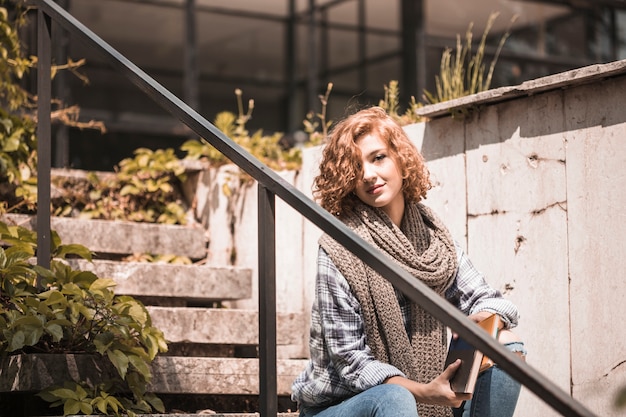 Free photo woman sitting on steps and holding books