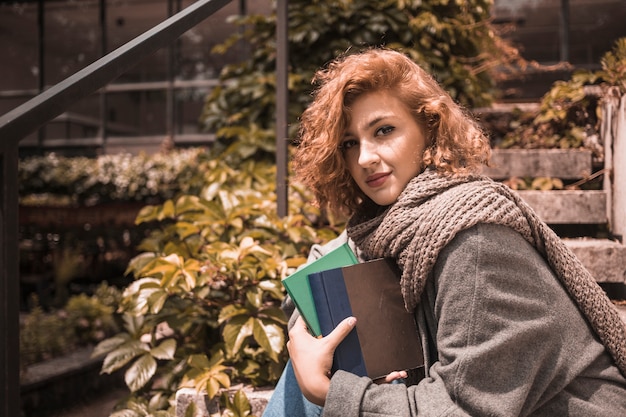 Free photo woman sitting on steps and holding books