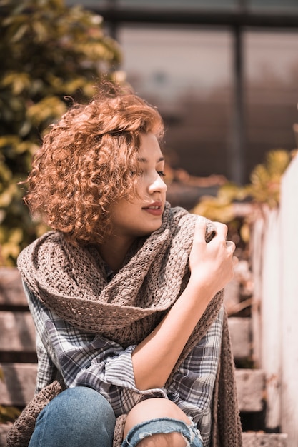 Free photo woman sitting on steps and holding scarf