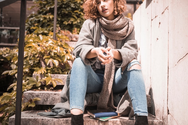 Free photo woman sitting on steps near books