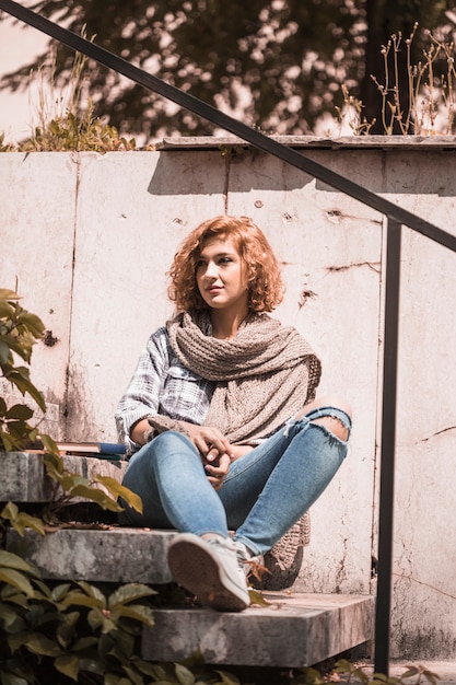 Free photo woman sitting on steps in public garden