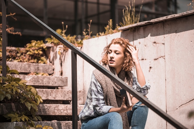 Free photo woman sitting on steps and readjusting hairs