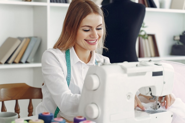 Free photo woman sitting in studio and sew cloth