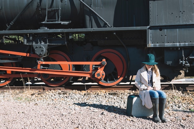 Free Photo woman sitting on suitcase at train