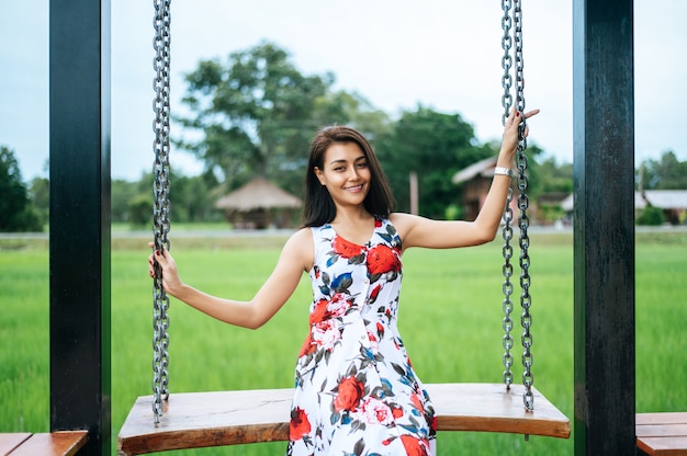 Free photo woman sitting on a swing and holding her hand at the chain